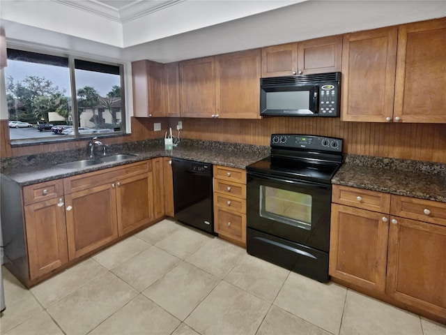 kitchen featuring sink, dark stone countertops, light tile patterned floors, ornamental molding, and black appliances