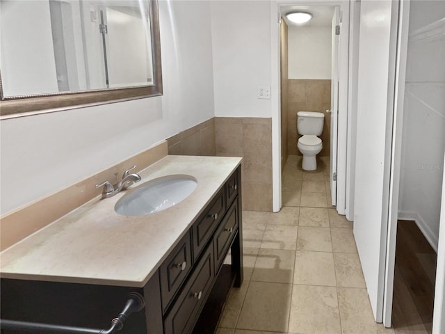 bathroom featuring tile walls, vanity, tile patterned flooring, and toilet