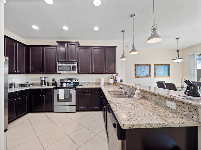 kitchen with dark brown cabinetry, appliances with stainless steel finishes, decorative light fixtures, sink, and light tile patterned floors