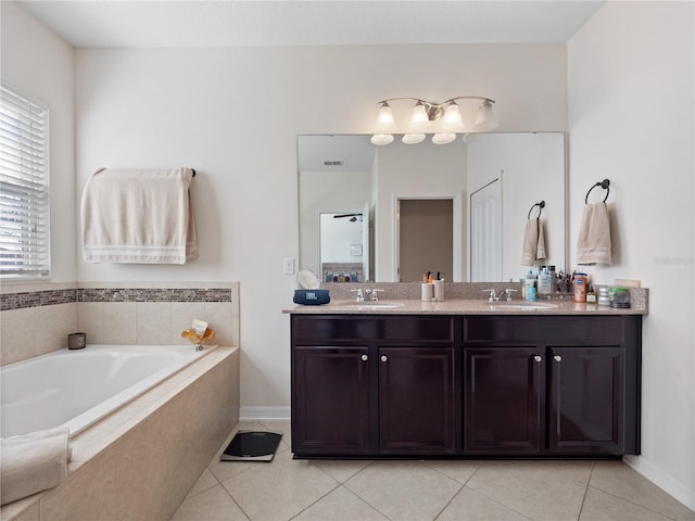 bathroom with vanity, a relaxing tiled tub, and tile patterned flooring