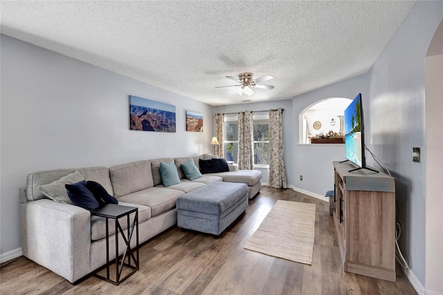 living room featuring ceiling fan, hardwood / wood-style flooring, and a textured ceiling