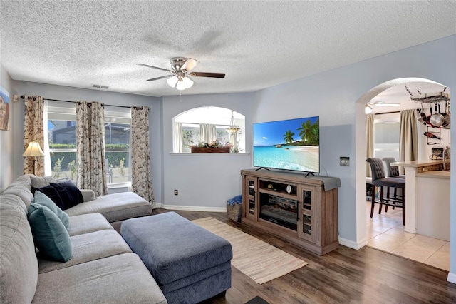 living room with dark hardwood / wood-style floors, a textured ceiling, and ceiling fan