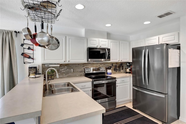 kitchen featuring white cabinetry, stainless steel appliances, sink, and a textured ceiling