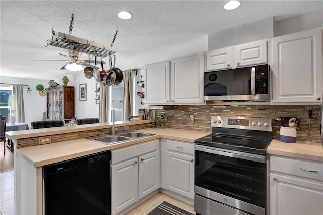 kitchen with sink, light tile patterned floors, appliances with stainless steel finishes, white cabinets, and kitchen peninsula