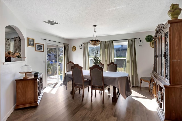 dining area featuring a textured ceiling, dark hardwood / wood-style floors, and a healthy amount of sunlight