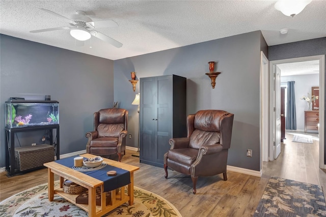 sitting room featuring ceiling fan, a textured ceiling, and light wood-type flooring