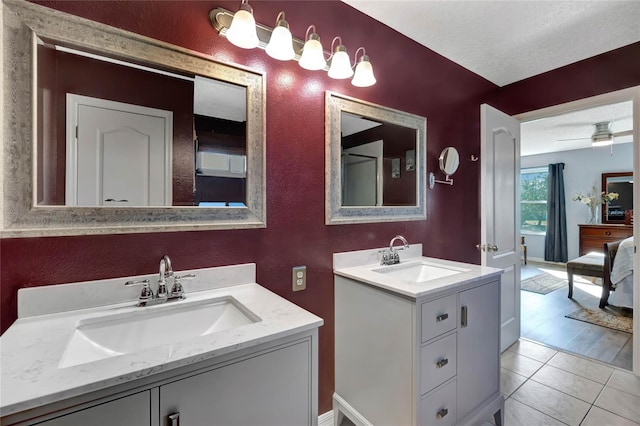 bathroom with tile patterned flooring, vanity, ceiling fan, and a textured ceiling