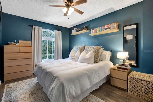 bedroom with dark wood-type flooring, a textured ceiling, and ceiling fan