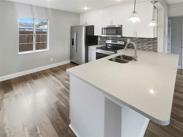 kitchen with kitchen peninsula, pendant lighting, sink, white cabinetry, and stainless steel appliances