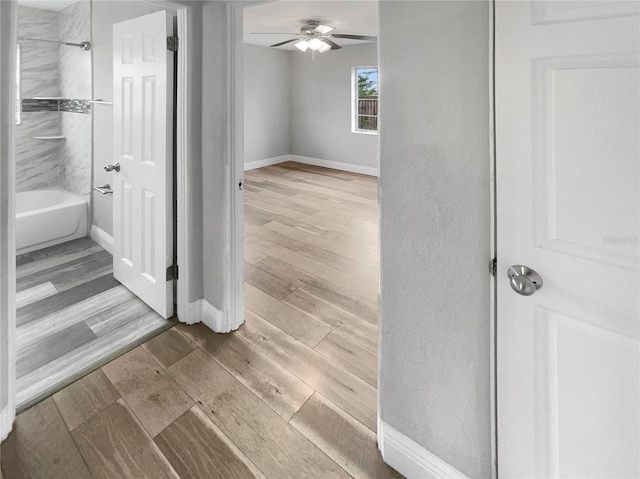 bathroom with ceiling fan and tiled shower / bath