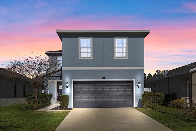 view of property with a garage and a lawn