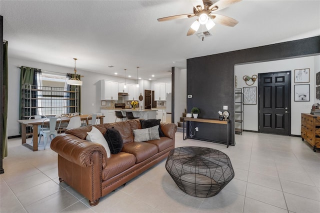 living room with ceiling fan, a textured ceiling, and light tile patterned floors