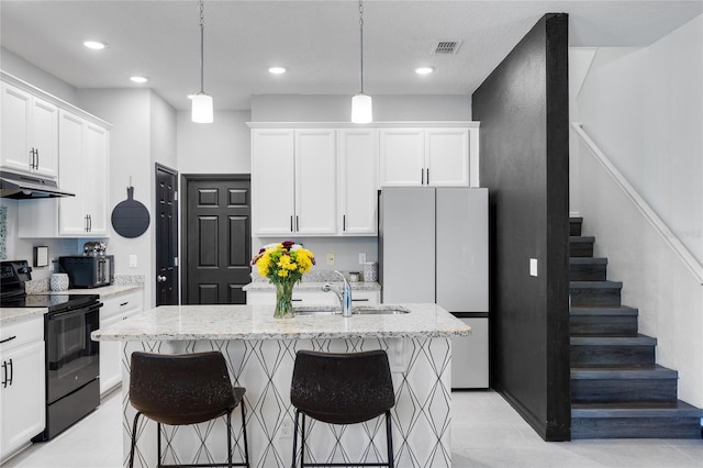 kitchen with hanging light fixtures, a center island with sink, black electric range, and white refrigerator