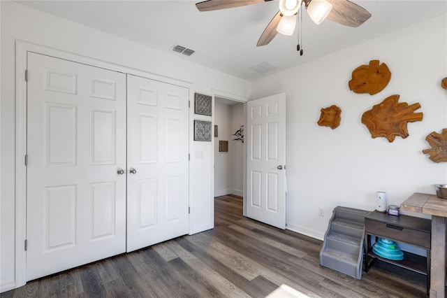 unfurnished bedroom featuring dark wood-type flooring, ceiling fan, and a closet