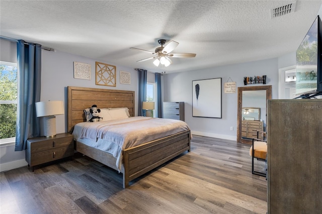 bedroom featuring multiple windows, dark hardwood / wood-style floors, and ceiling fan