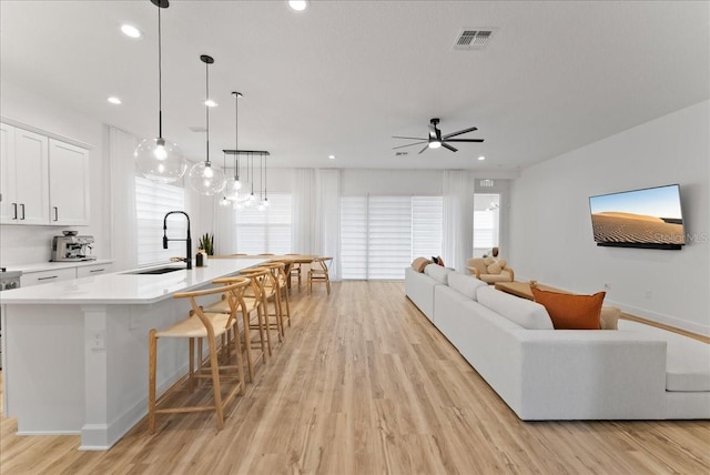 living room featuring sink, ceiling fan, and light hardwood / wood-style flooring