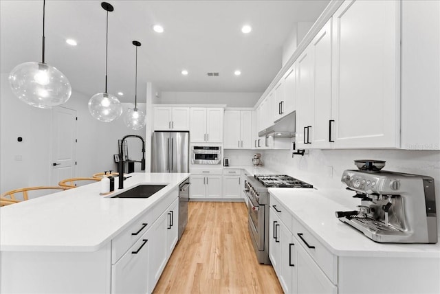 kitchen with white cabinetry, sink, pendant lighting, an island with sink, and stainless steel appliances