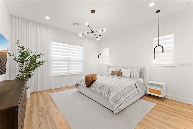 bedroom with light wood-type flooring and a notable chandelier