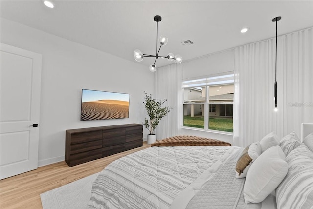 bedroom with light hardwood / wood-style floors and a notable chandelier