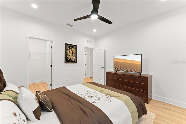 bedroom featuring ceiling fan, a closet, a walk in closet, and light wood-type flooring