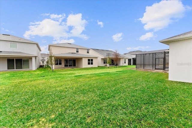 rear view of property with a lanai and a lawn