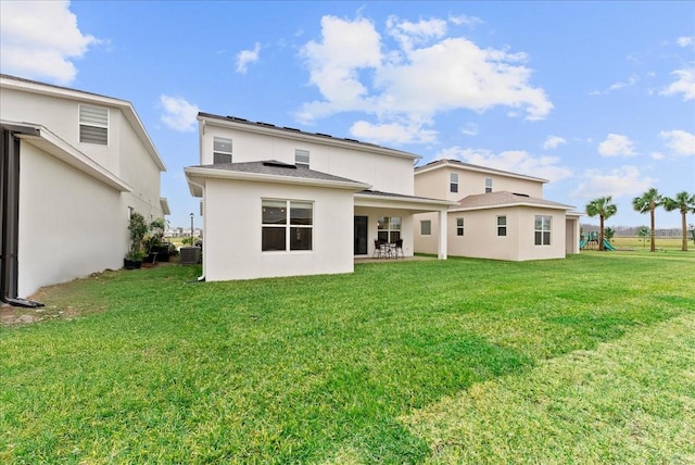 back of house featuring central AC unit, a yard, and a playground