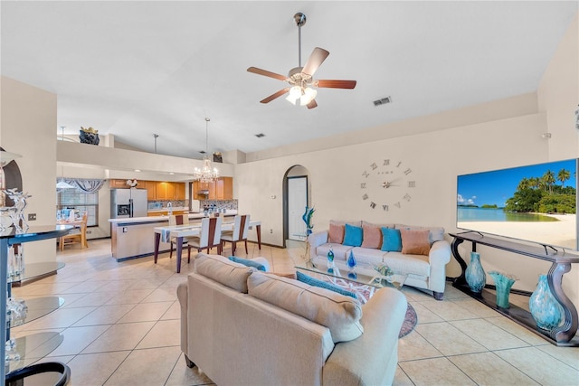 tiled living room featuring ceiling fan with notable chandelier and vaulted ceiling