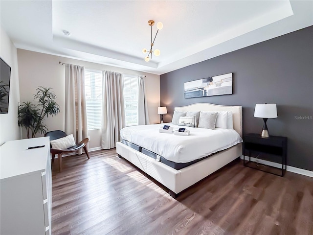 bedroom with dark hardwood / wood-style floors and a tray ceiling