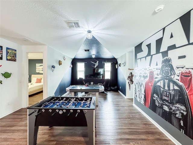 recreation room with hardwood / wood-style flooring, a textured ceiling, and lofted ceiling