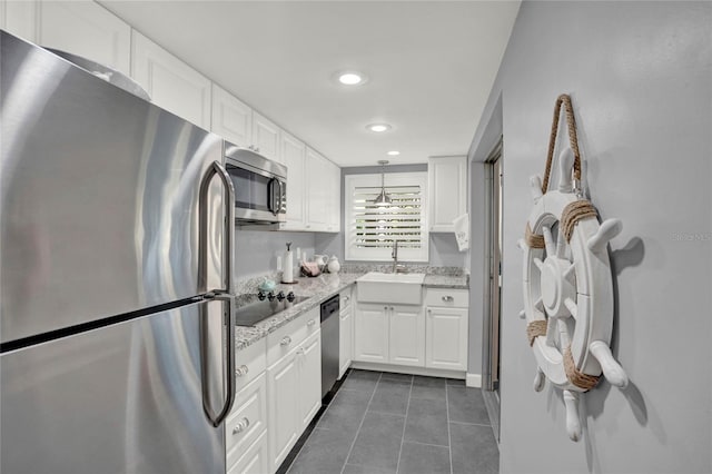 kitchen featuring appliances with stainless steel finishes, decorative light fixtures, white cabinetry, sink, and light stone counters