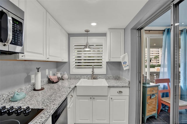 kitchen with decorative light fixtures, sink, white cabinets, and stainless steel appliances