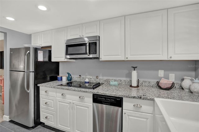 kitchen with sink, white cabinetry, dark tile patterned floors, and appliances with stainless steel finishes