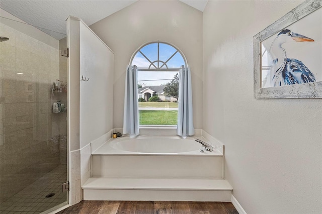 bathroom with wood-type flooring, a textured ceiling, and independent shower and bath