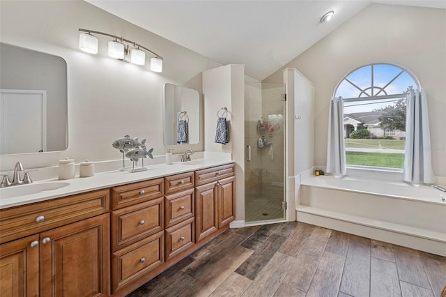 bathroom featuring independent shower and bath, lofted ceiling, and vanity