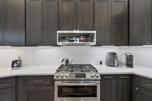 kitchen with dark brown cabinets, decorative backsplash, and appliances with stainless steel finishes