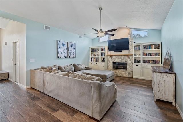 living room featuring ceiling fan, vaulted ceiling, and a fireplace