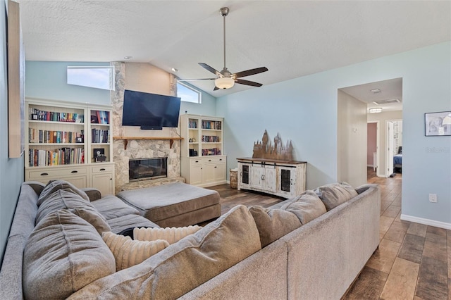 living room with ceiling fan, a textured ceiling, a stone fireplace, and vaulted ceiling