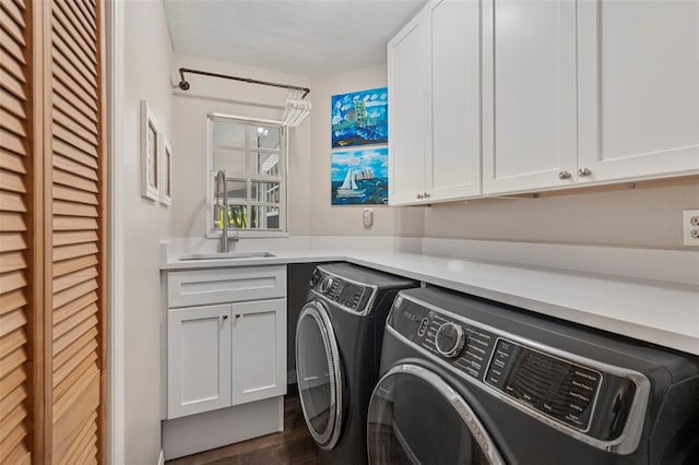 laundry room featuring cabinets, dark hardwood / wood-style floors, sink, and washing machine and clothes dryer