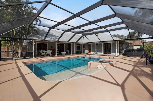 view of pool with an in ground hot tub, a patio area, and glass enclosure