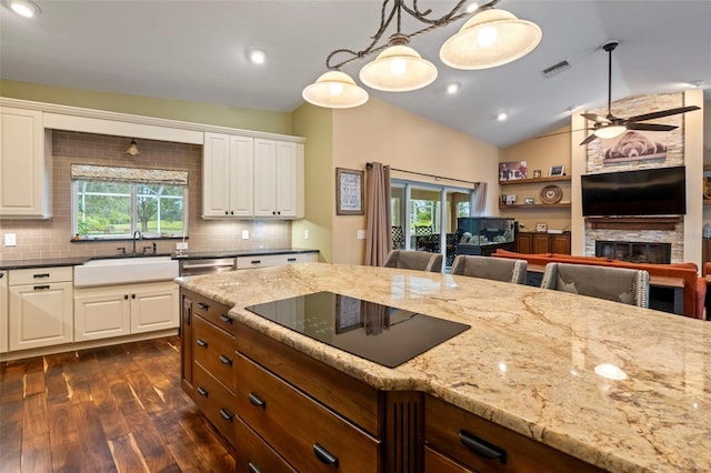 kitchen with sink, hanging light fixtures, lofted ceiling, and black electric cooktop