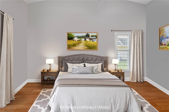 bedroom with wood-type flooring and vaulted ceiling