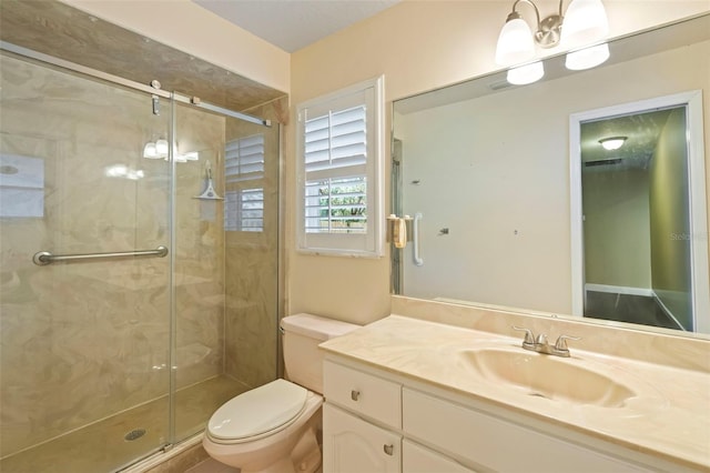 bathroom featuring a shower with shower door, toilet, and vanity