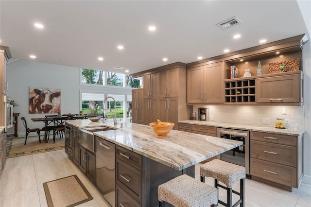 kitchen featuring dishwasher, sink, beverage cooler, backsplash, and a center island with sink