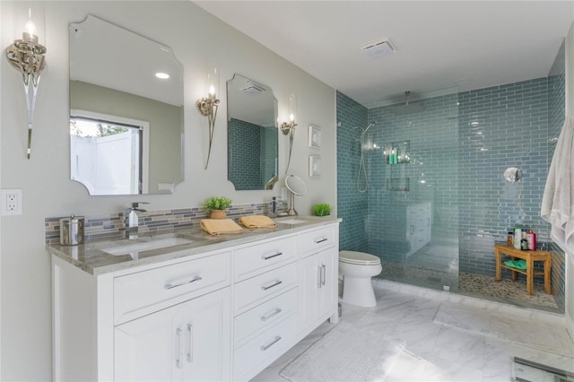 bathroom featuring tasteful backsplash, vanity, tiled shower, and toilet