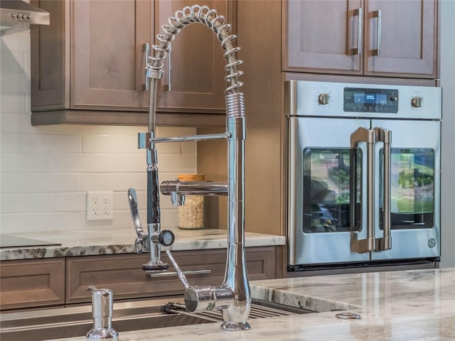 interior space with light stone counters, decorative backsplash, and oven