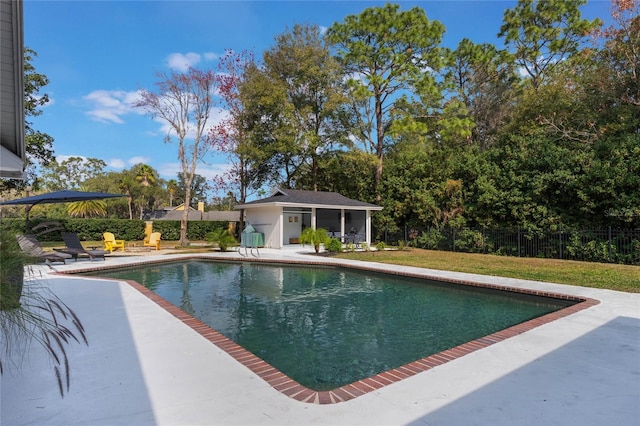 view of swimming pool featuring a yard, an outbuilding, and a patio area