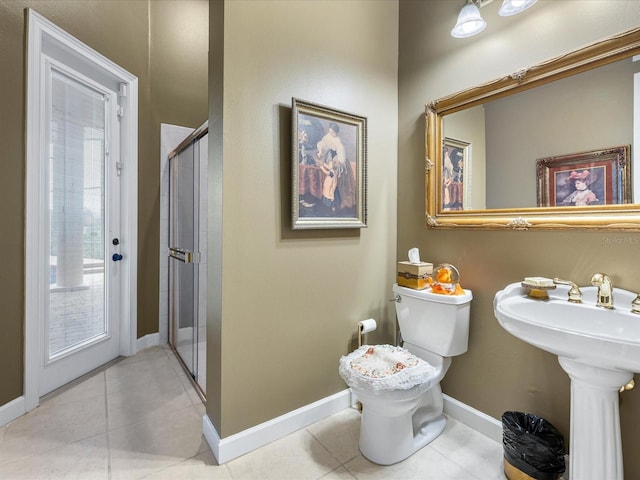 bathroom featuring sink, a shower with shower door, tile patterned floors, and toilet