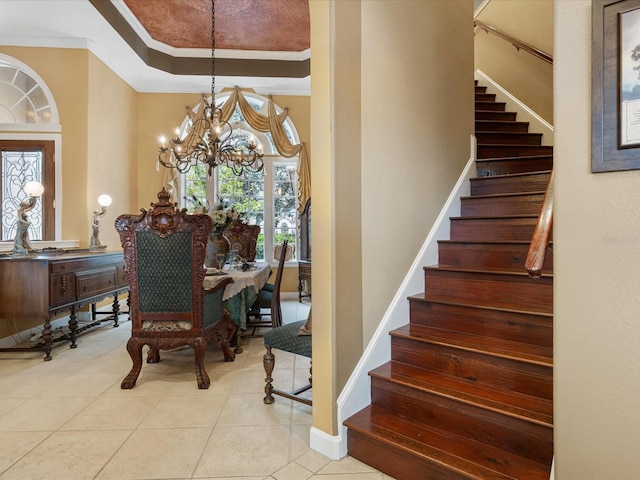 interior space featuring crown molding, a tray ceiling, tile patterned floors, and an inviting chandelier