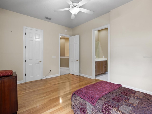 bedroom with ceiling fan, ensuite bath, and light wood-type flooring