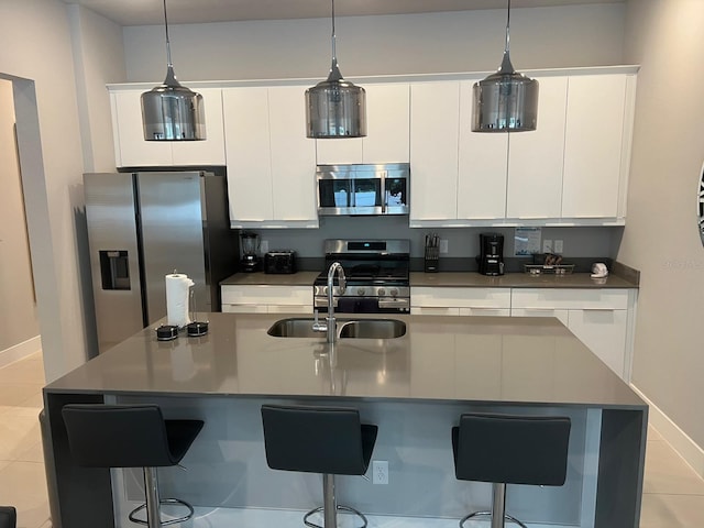 kitchen with a kitchen bar, white cabinetry, stainless steel appliances, and light tile patterned flooring